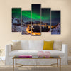 A man looking at the Northern lights over Reine, Lofoten islands, Norway Multi panel canvas wall art