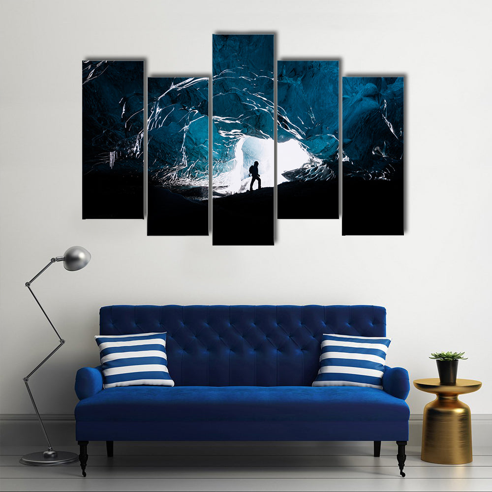 Man exploring an amazing glacial cave in Iceland Multi Panel Canvas Wall Art