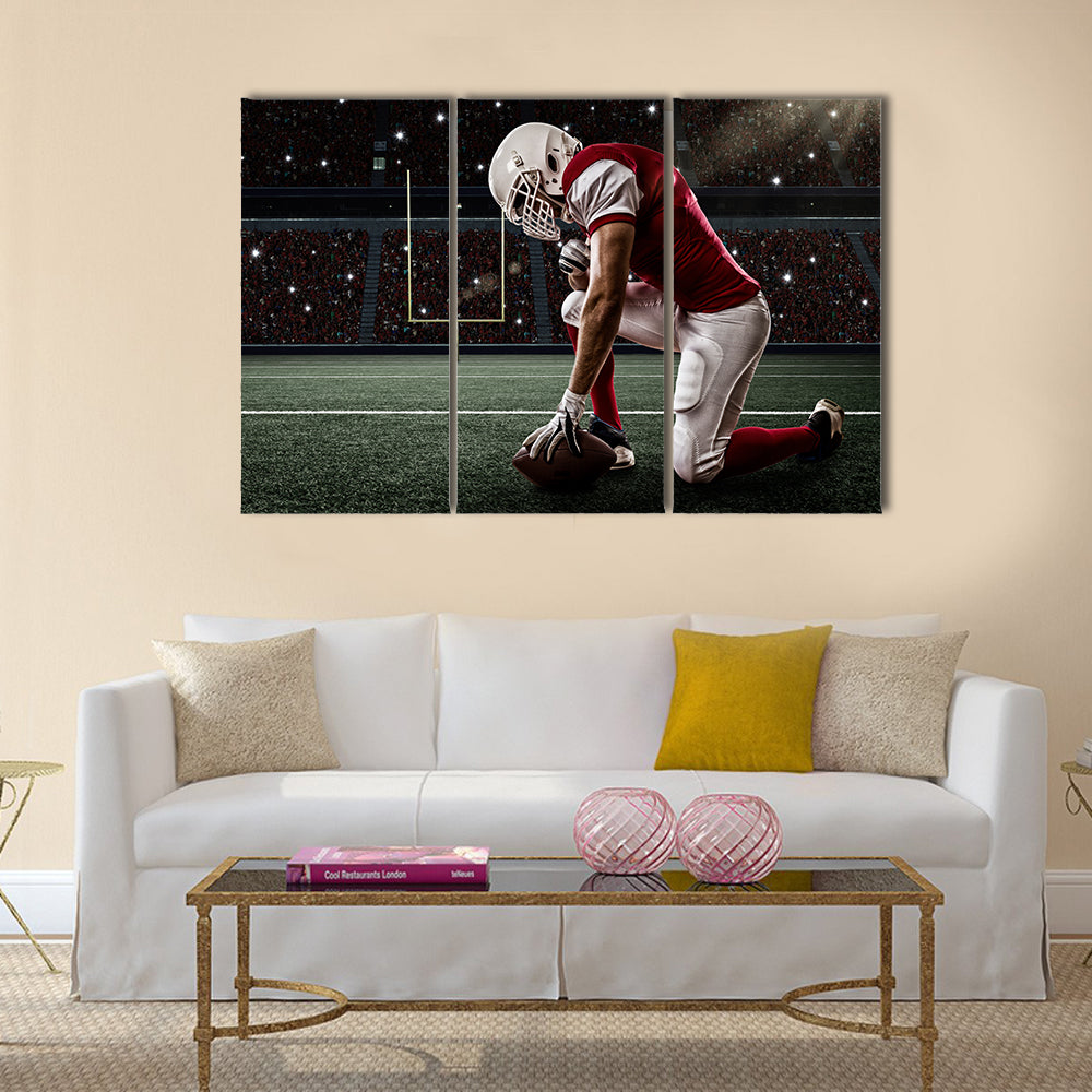 Football Player with a red uniform on his knees, on a Stadium Multi panel canvas wall art