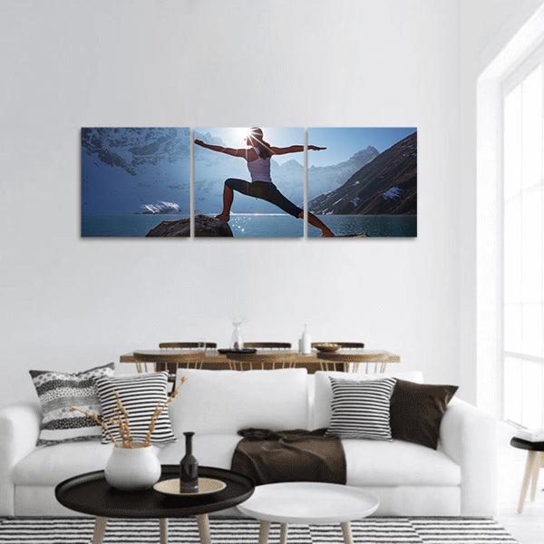 Young woman is practicing yoga at mountain lake panoramic canvas wall art