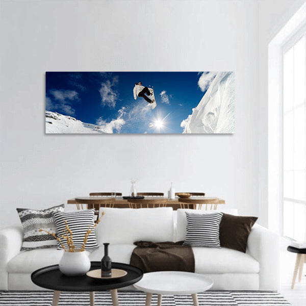 Snowboarder jumping through the air with blue sky panoramic canvas wall art