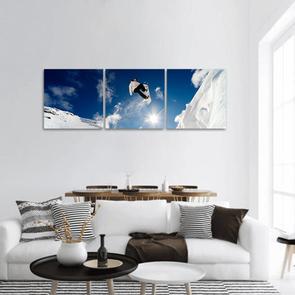 Snowboarder jumping through the air with blue sky panoramic canvas wall art