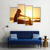 Silhouette of a fitness woman stretching at sunset with the sun in the background, Multi panel canvas wall art