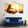 Silhouette of a fitness woman stretching at sunset with the sun in the background, Multi panel canvas wall art