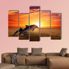 Marine life background - jumping dolphins, beautiful red sunset on sea Multi panel canvas wall art