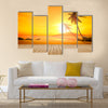 A beautiful sunset over the ocean with a palm tree and wooden jetty foreground Multi panel canvas wall art