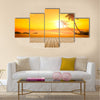 A beautiful sunset over the ocean with a palm tree and wooden jetty foreground Multi panel canvas wall art