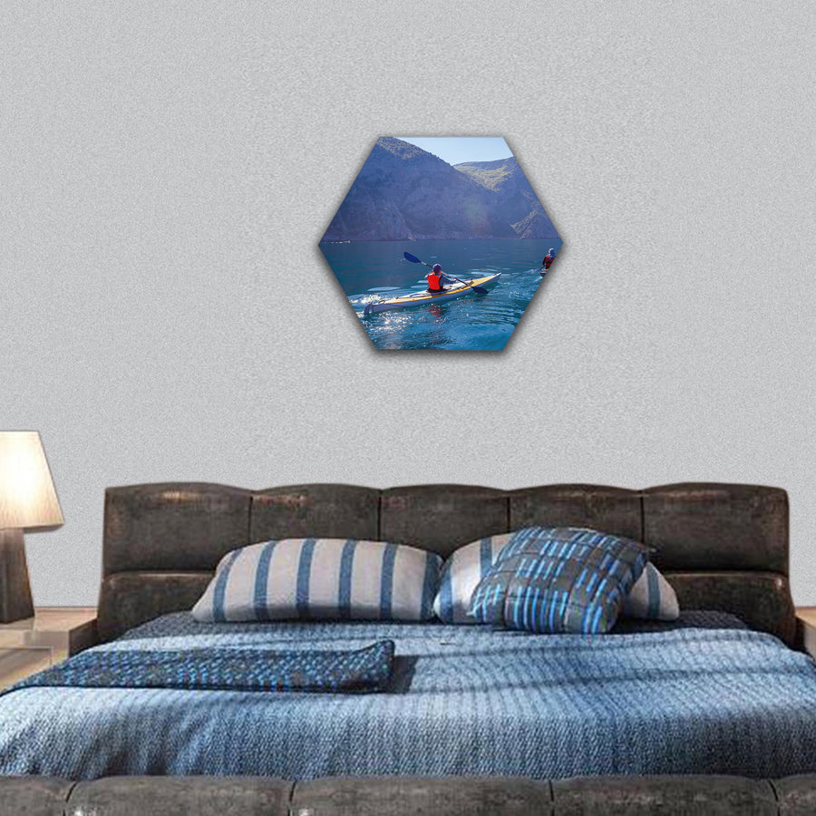 People kayaking in the sea near the mountains hexagonal canvas wall art
