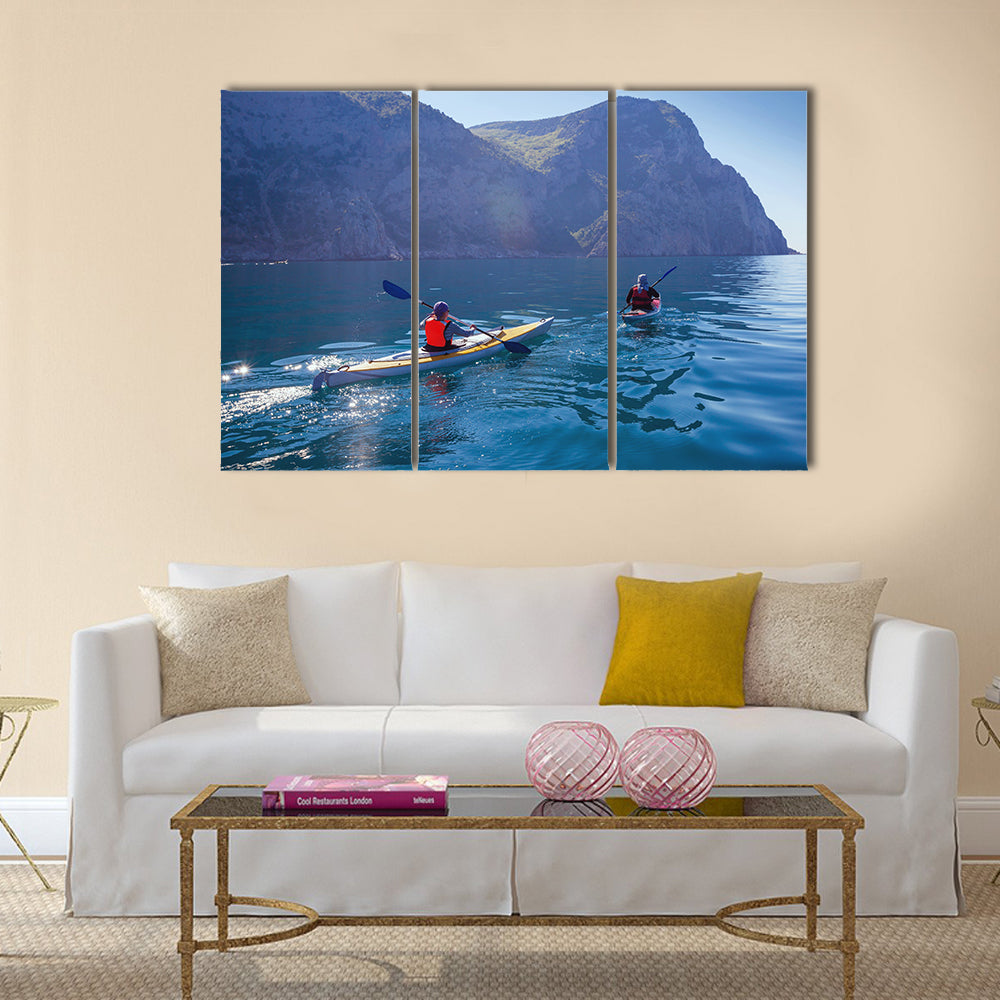 People kayaking in the sea near the mountains multi panel canvas wall art