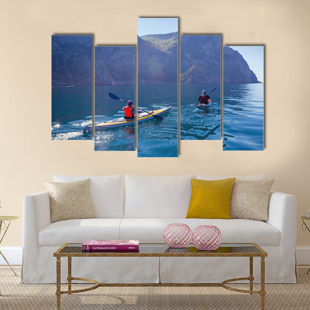 People kayaking in the sea near the mountains multi panel canvas wall art