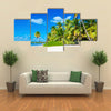 Amazing tropical beach with palm tree entering the ocean against Azur Ocean, gold sand and blue sky Multi panel canvas wall art