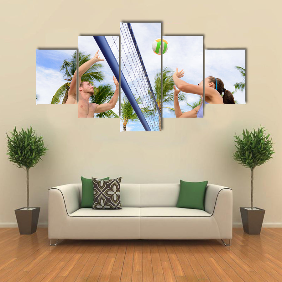 Woman and man having fun in volley ball game in summer Multi panel canvas wall art