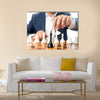 Closeup photo of businessman playing chess and beating black king multi panel canvas wall art