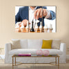 Closeup photo of businessman playing chess and beating black king multi panel canvas wall art