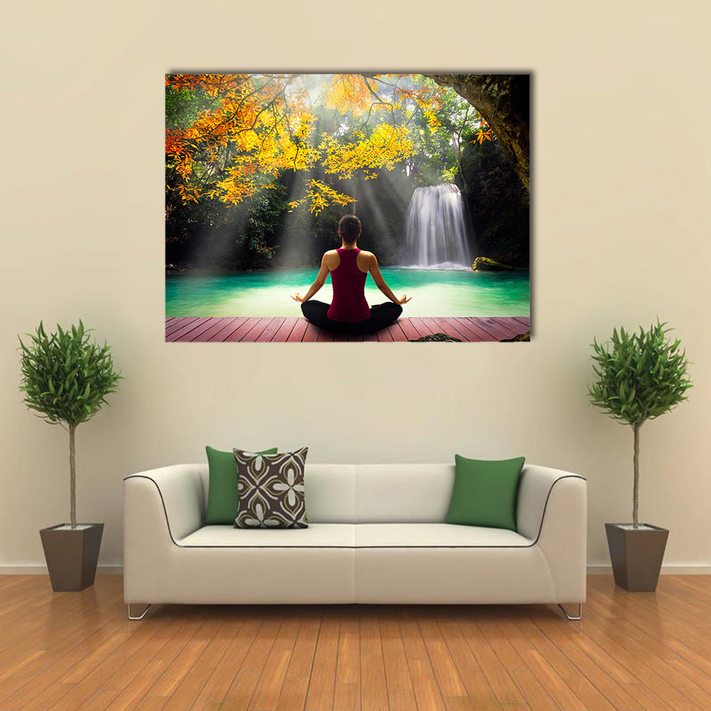 Young woman in yoga pose sitting near waterfall Rear view