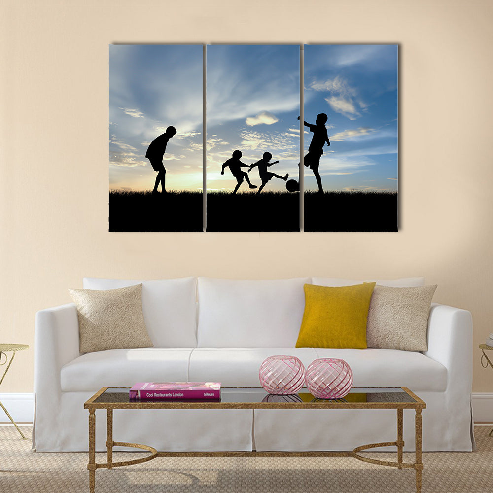 Silhouette boys playing football at sunset Multi panel canvas wall art
