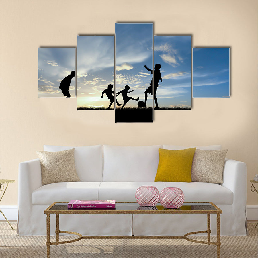 Silhouette boys playing football at sunset Multi panel canvas wall art