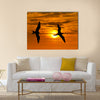 Two birds flying silhouette with a clowing beautiful orange and yellow sunset beaming in the background Multi panel canvas wall art