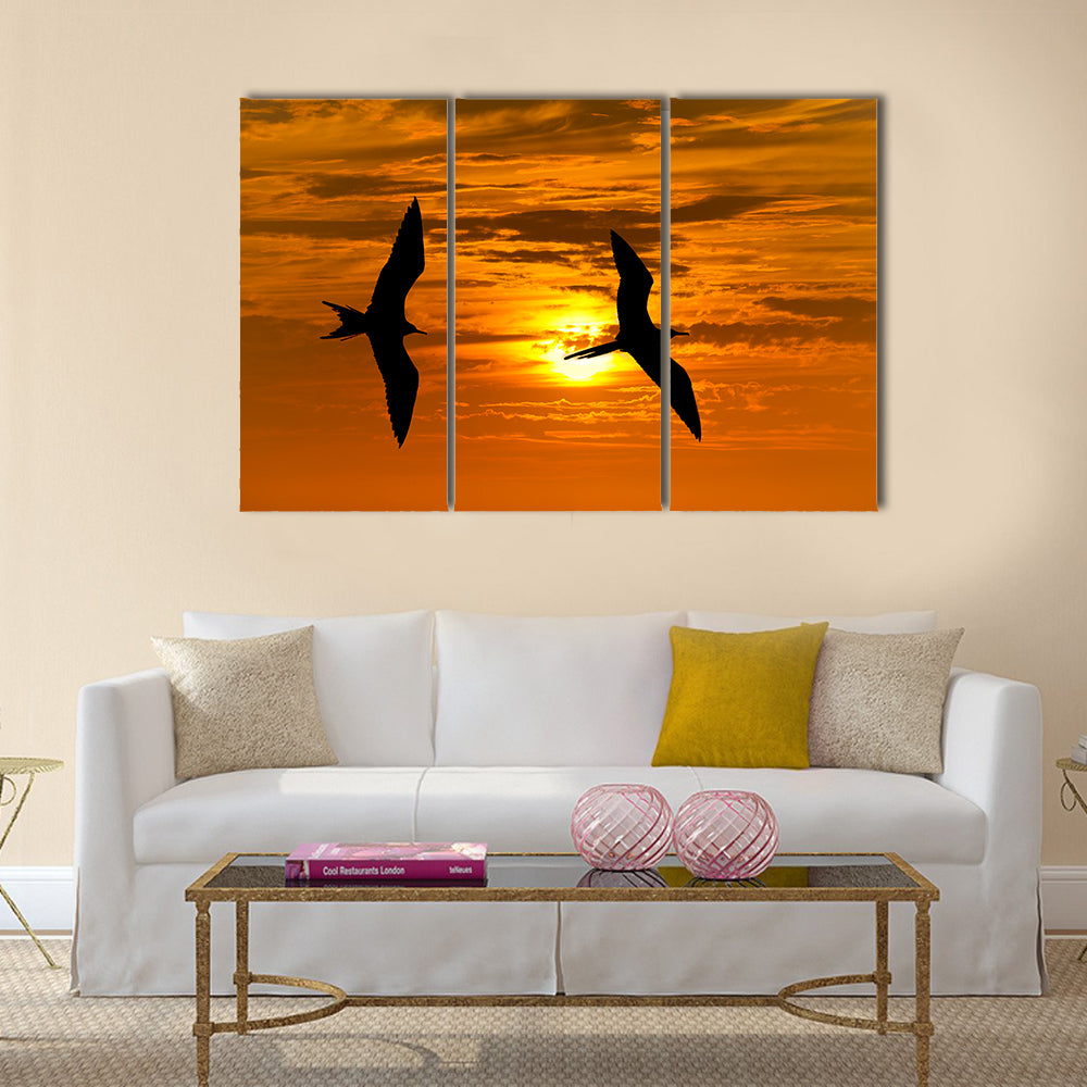Two birds flying silhouette with a clowing beautiful orange and yellow sunset beaming in the background Multi panel canvas wall art