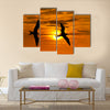 Two birds flying silhouette with a clowing beautiful orange and yellow sunset beaming in the background Multi panel canvas wall art