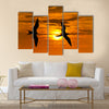 Two birds flying silhouette with a clowing beautiful orange and yellow sunset beaming in the background Multi panel canvas wall art