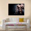 Handsome young man in shorts, doing exercises for biceps, on a dark background in the studio, Multi panel canvas wall art