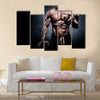 Handsome young man in shorts, doing exercises for biceps, on a dark background in the studio, Multi panel canvas wall art