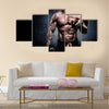 Handsome young man in shorts, doing exercises for biceps, on a dark background in the studio, Multi panel canvas wall art