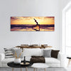 Silhouette of woman practicing yoga on beach at sunset Panoramic Canvas Wall Art