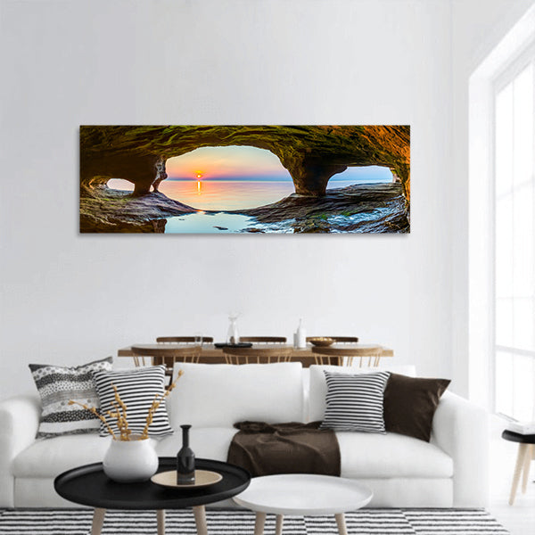 The setting sun is viewed from sea cave panoramic canvas wall art