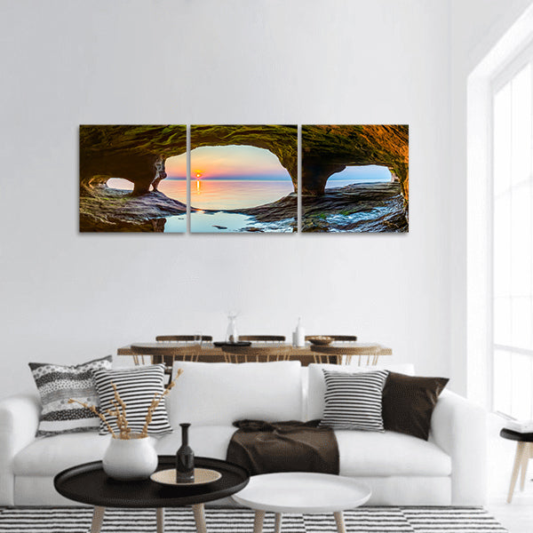 The setting sun is viewed from sea cave panoramic canvas wall art