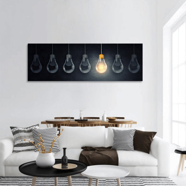 Light bulbs on dark background with one glowing panoramic canvas wall art