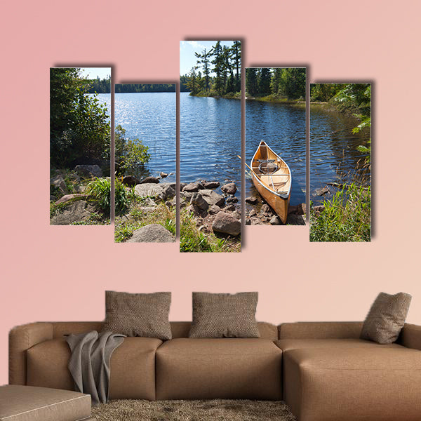 A yellow fisherman's canoe on a rocky shore of multi panel canvas wall art