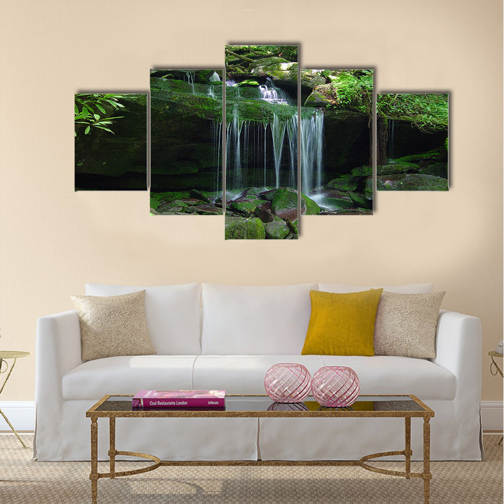 A small water fall flows on a rock ledge Multi Panel Canvas Wall Art