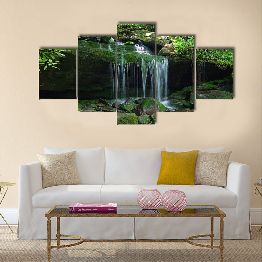 A small water fall flows on a rock ledge Multi Panel Canvas Wall Art