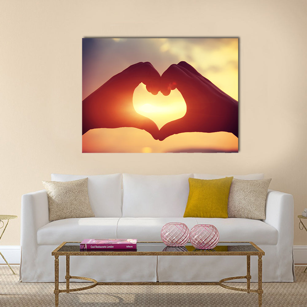 Heart shape making of hands against bright sea sunset multi panel canvas wall art