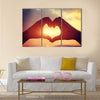 Heart shape making of hands against bright sea sunset multi panel canvas wall art