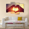 Heart shape making of hands against bright sea sunset multi panel canvas wall art