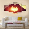 Heart shape making of hands against bright sea sunset multi panel canvas wall art