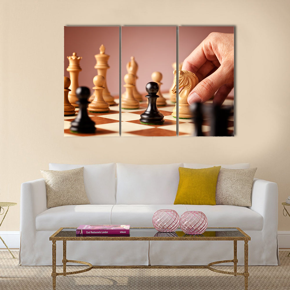 Male hand moving the white chess knight multi panel canvas wall art