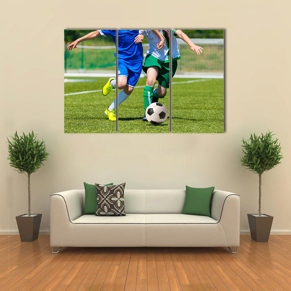 Young boys playing football soccer game running players in blue and white uniforms Multi panel canvas wall art