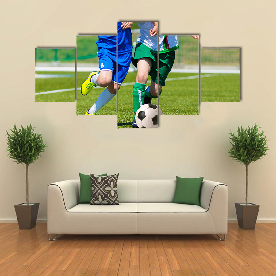 Young boys playing football soccer game running players in blue and white uniforms Multi panel canvas wall art