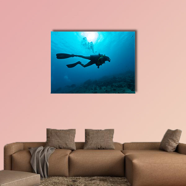 Young female scuba diver silhouette swimming underwater Multi panel canvas wall art