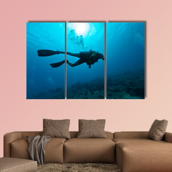 Young female scuba diver silhouette swimming underwater Multi panel canvas wall art