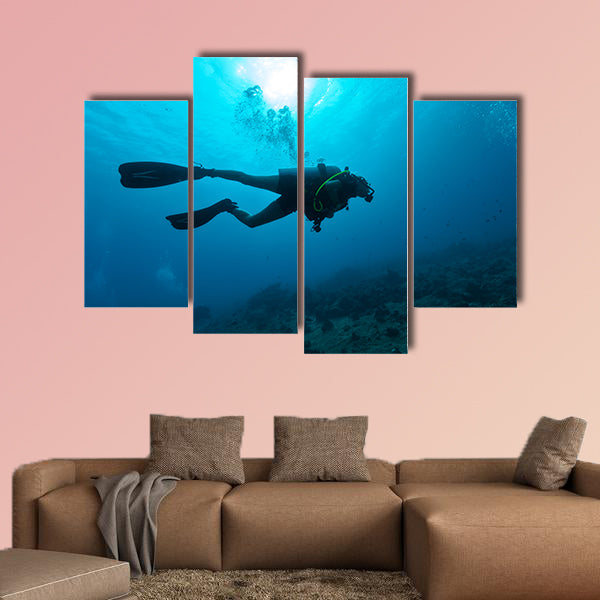 Young female scuba diver silhouette swimming underwater Multi panel canvas wall art