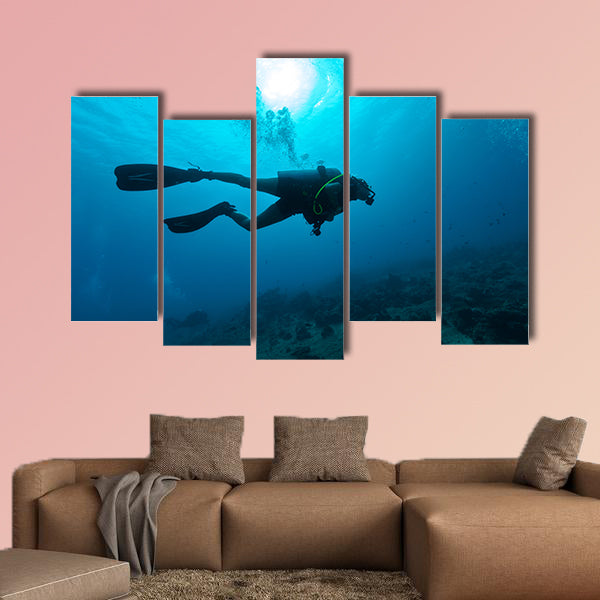 Young female scuba diver silhouette swimming underwater Multi panel canvas wall art