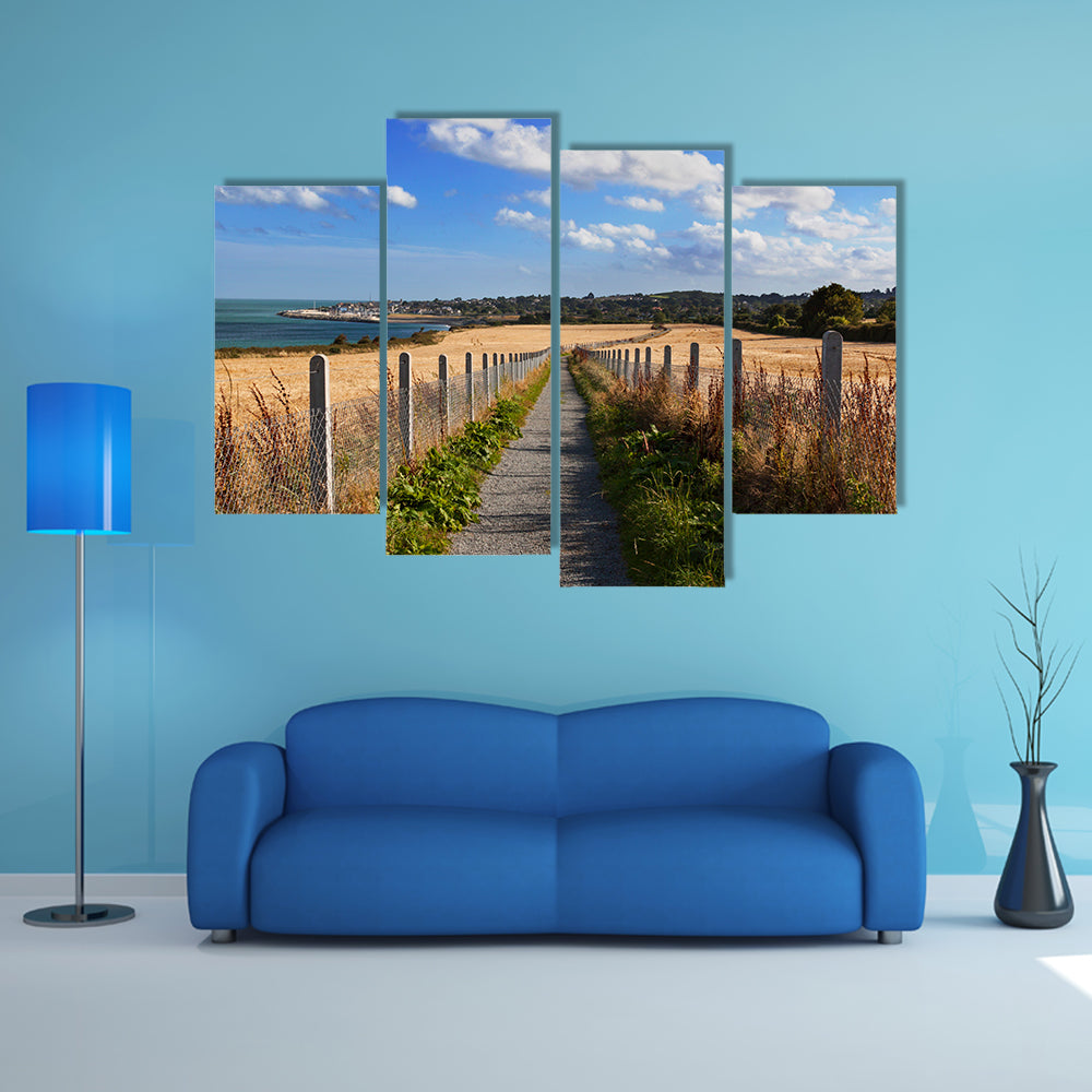 Narrow road with field of wheat on the sides with sea and city wall art