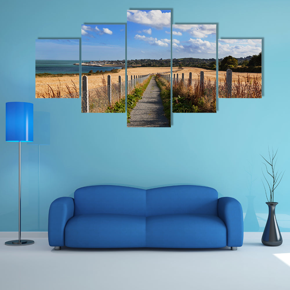 Narrow road with field of wheat on the sides with sea and city wall art
