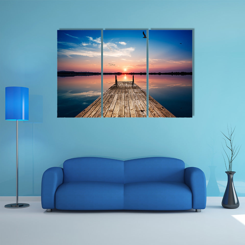 Perspective view of a wooden pier on the pond at sunset with perfectly specular reflection multi panel canvas wall art