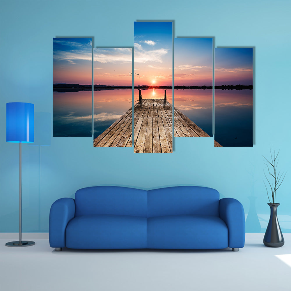 Perspective view of a wooden pier on the pond at sunset with perfectly specular reflection multi panel canvas wall art